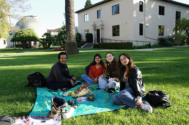 Four students sit on the grass outside Varsi Hall