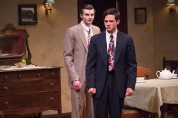 Two men in suits standing in a furnished room.