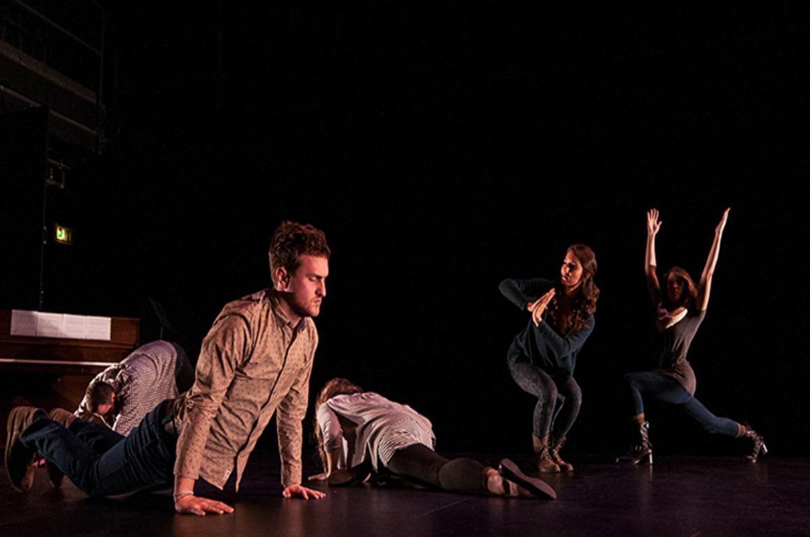 Three performers on a dimly lit stage during 