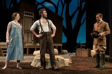 Three people in period costumes performing a scene on stage outdoors at night.