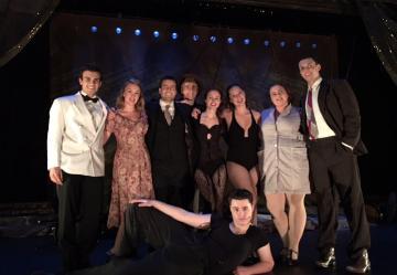 A group of individuals posing on stage in formal wear. 'The Cast'