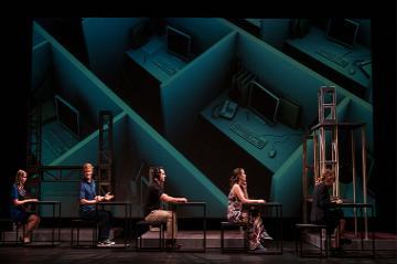 People working at desks in front of a geometric background.