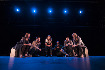 A group of dancers performs under stage lights.