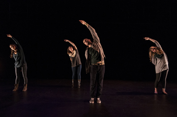 People dancing on stage in coordinated poses.