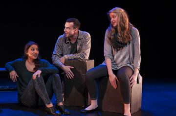 Three people sitting and talking on stage with a dark backdrop.