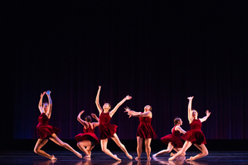 Dancers in red costumes performing on stage.