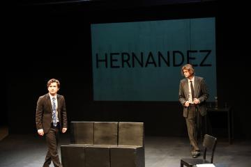 2 men in suits against a backdrop with the word Hernandez projected