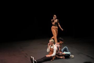 Male & Female college students sitting on the ground with a female college student standing talking on a phone