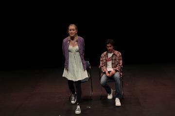 Male college student seated, female college student standing