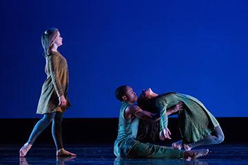 Two dancers performing on stage against a blue background.