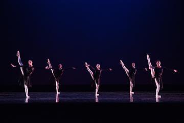 Dancers performing on a stage under blue lighting.