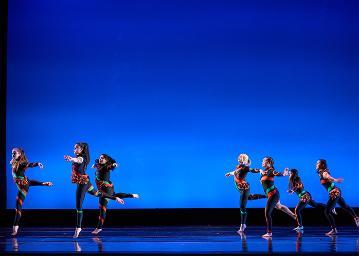 A group of 3 female dancers on the left and a group of 4 female dancers on the right wearing black unitards with monarch butterfly abstract markings