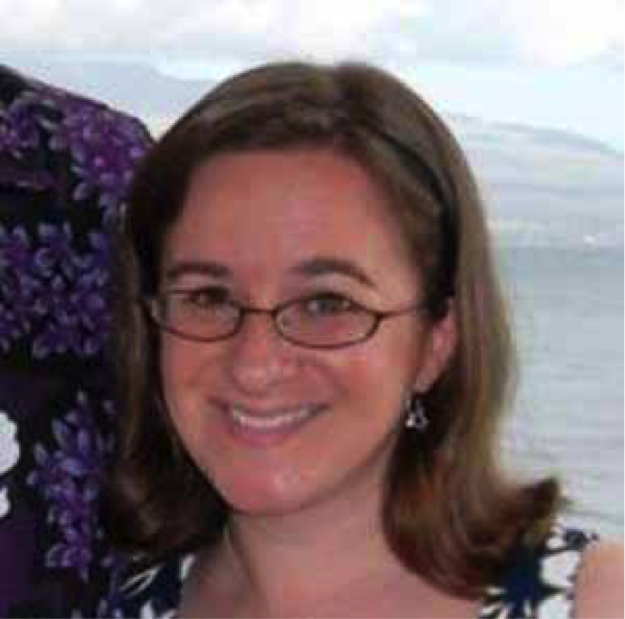 A person wearing glasses smiling with the sea and mountains in the background.