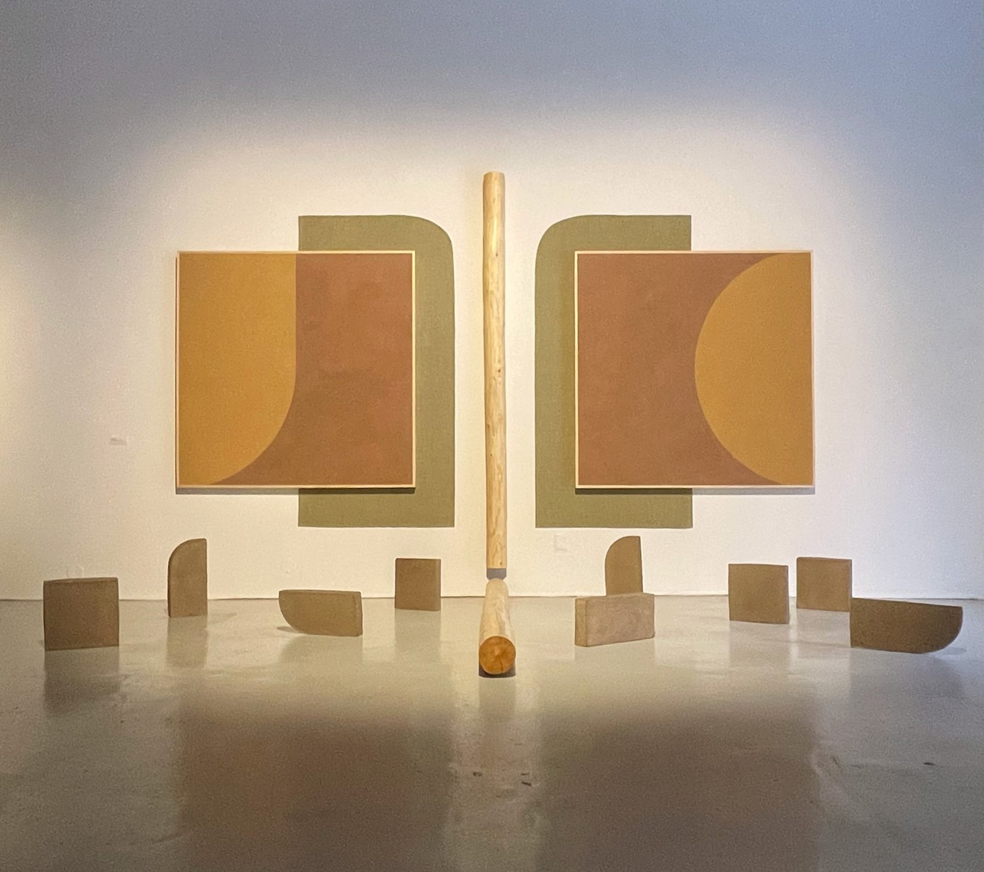 Photograph of installation featuring adobe and wood sculptures in geometric shapes and wall panels