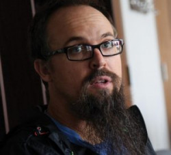 A person with glasses and a beard looking at the camera.