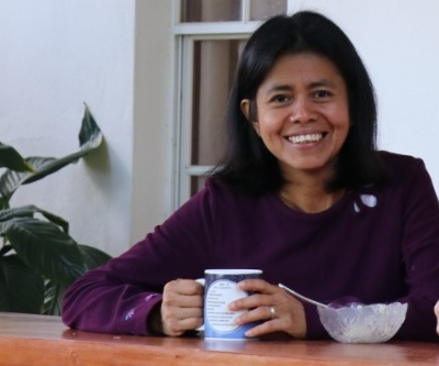 A person smiling while holding a coffee mug.