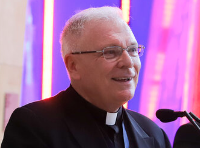 A man in clerical attire speaking at an event.