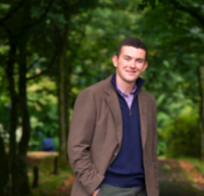 A person standing outdoors in a wooded area.