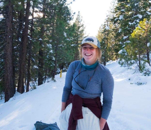 A person smiling in a snowy forest.