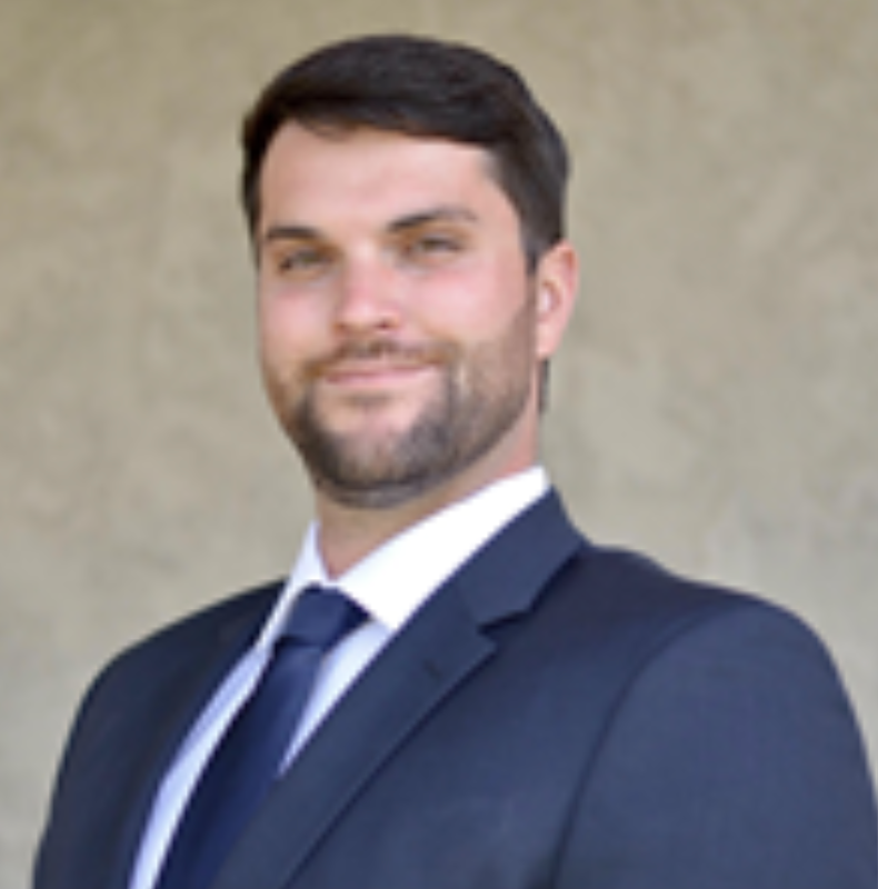 A person in a suit posing against a neutral background.