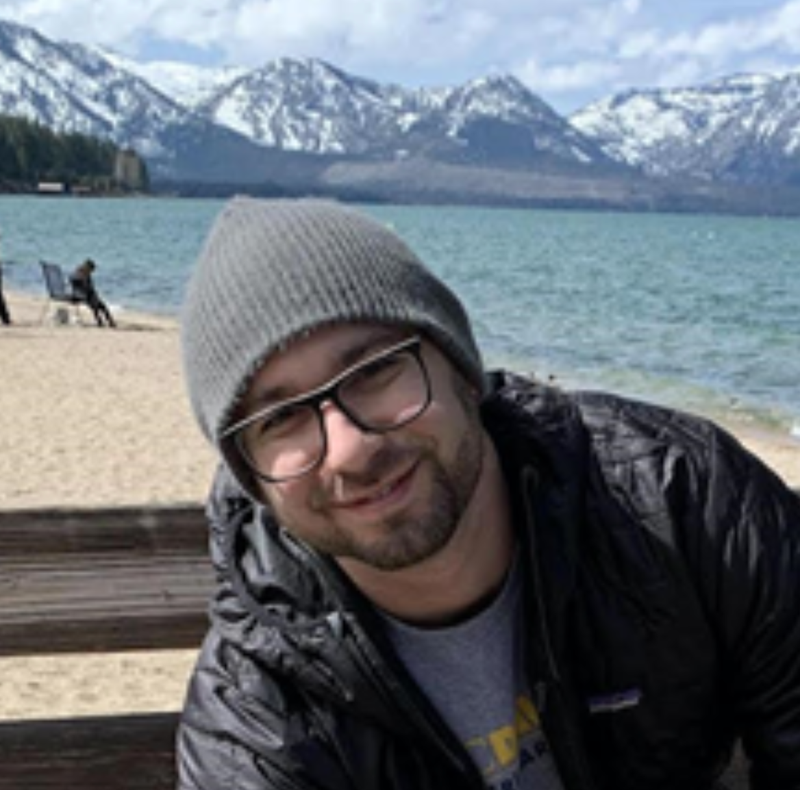 A person in front of a lake with snowy mountains in the background.