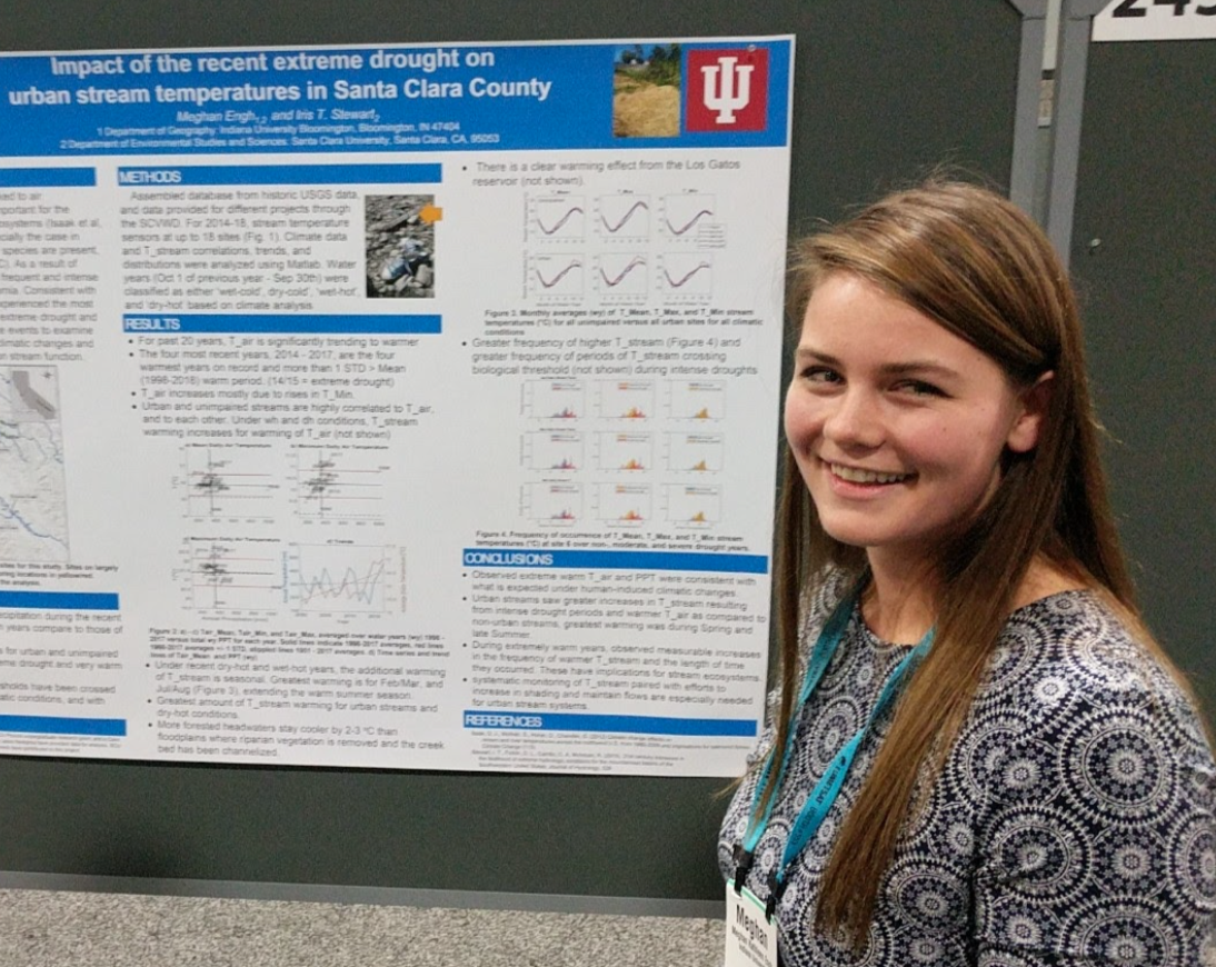 A woman smiling in front of a scientific research poster.