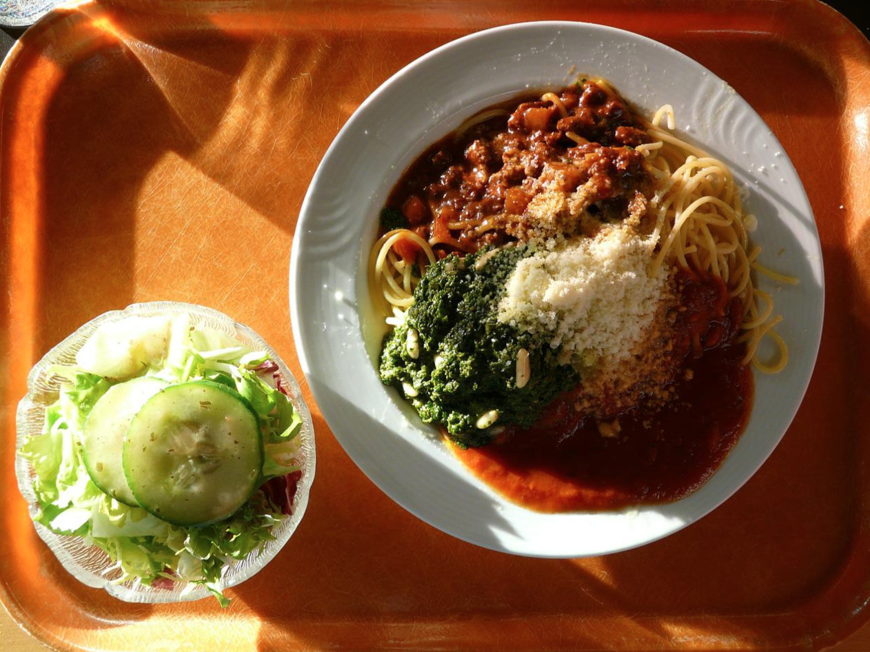 Plate of assorted food and salad bowl on an orange tray.