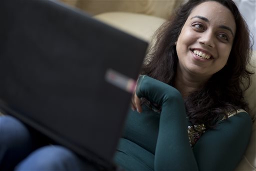 A person smiling while using a laptop. image link to story