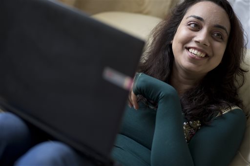 A person smiling while using a laptop.