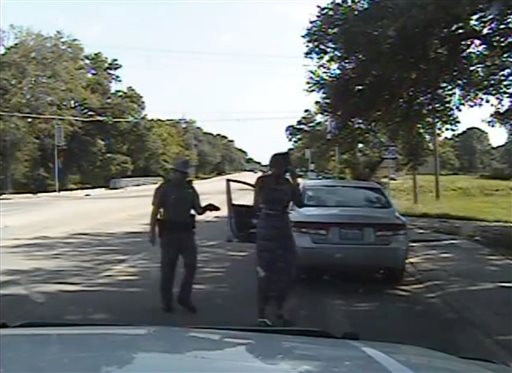 Two police officers standing near a car on a tree-lined road. image link to story