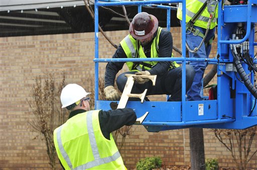 Construction workers fixing a wall using a blue lifting platform.