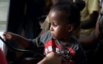 medical professional listens to a child's heartbeat through a stethoscope