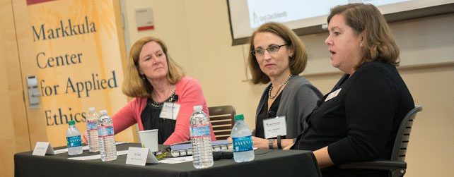 Three people discussing gender diversity at a conference panel.