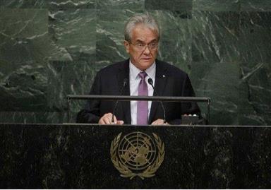 A person speaking at a podium with the United Nations emblem.