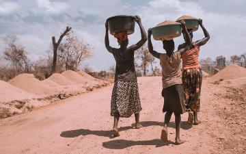 Three women carrying basins on their heads. Photo credit: Ninno JackJr/Unspash 