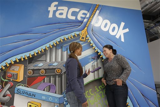 Two people standing in front of a Facebook mural. image link to story