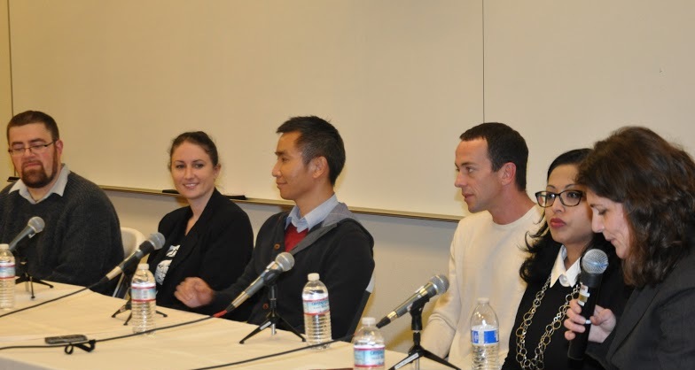 A panel of five people speaking into microphones at a table. image link to story
