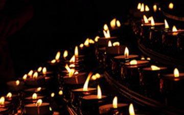 Alt text: Numerous lit candles in a dark setting. image link to story