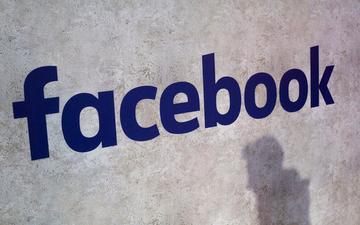 Facebook logo on a wall with a shadow.