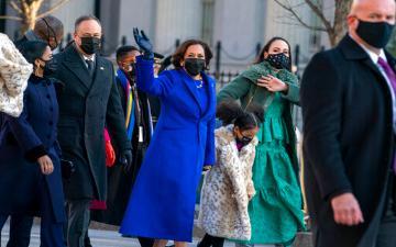 Vice President Kamala Harris in a blue coat with others, all wearing masks.