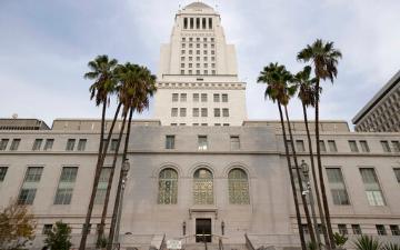 Los Angeles City Hall with palm trees in the foreground.
