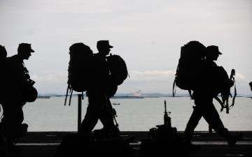 Service members carrying duffle bags and equipment