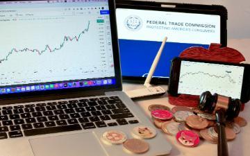 Laptop, tablet, and smartphone displaying charts and Bitcoin logos on a desk.