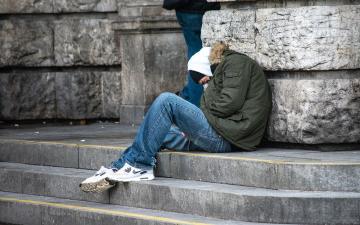 homeless woman leaning against a building