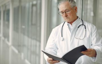 A doctor with a stethoscope reviews notes in a folder.