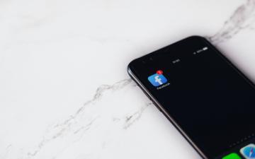 A smartphone displaying the Facebook app icon on a marble surface.