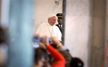 Pope Francis greeting people in a corridor.