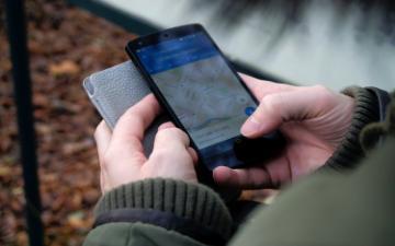 hands of person outdoors using smartphone with google map application