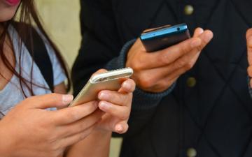 Two people texting with mobile phones. image link to story