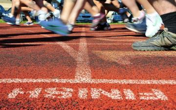 Alt text: Runners' feet on a track near the finish line.